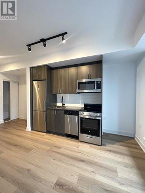 Toronto (Dovercourt-Wallace Emerson-Junction) condo for rent - A modern kitchen with wooden cabinets and stainless steel appliances.