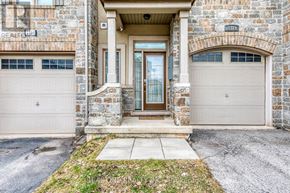 Oakville (Wm Westmount) townhouse for rent - A stone building with a brown door and two garage doors.
