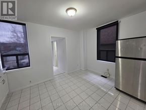 Toronto (Dovercourt-Wallace Emerson-Junction) apartment for rent - A white tiled kitchen with a stainless steel refrigerator and a window.