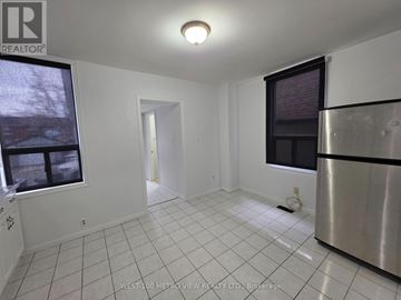 Toronto (Dovercourt-Wallace Emerson-Junction) apartment for rent - A white tiled kitchen with a stainless steel refrigerator and a window.