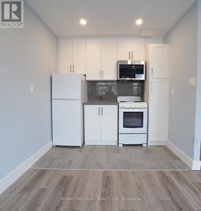Toronto (East End-Danforth) multi-family for rent - A kitchen with white cabinets and appliances in a model home.