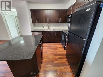 Mississauga (City Centre) condo for rent - A kitchen with a black refrigerator and wooden floors.