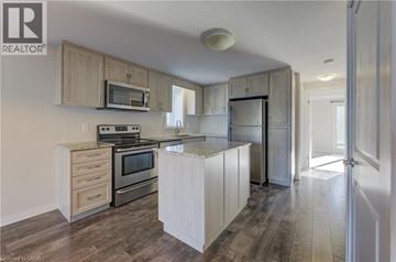 Kitchener townhouse for rent - A kitchen with wooden cabinets and a microwave above the stove.