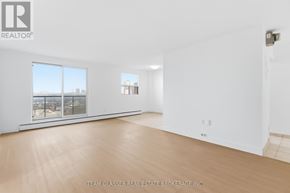 London East (East F) condo for rent - A large empty room with a view of the city through the windows.