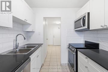 London East (East F) condo for rent - A kitchen with white cabinets and black countertops.