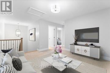 Quinte West (Murray Ward) townhouse for rent - A living room with a grey sofa, a coffee table, and a television on a cabinet.