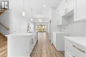 Quinte West (Murray Ward) townhouse for rent - A spacious kitchen with white cabinets and a wooden floor.