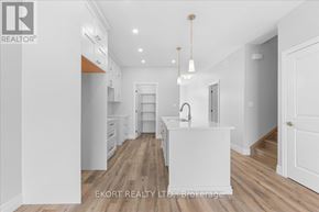 Quinte West (Murray Ward) townhouse for rent - A white kitchen with wooden floors and a white island.