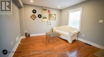 St. Catharines (Downtown) apartment for rent - A living room with a white couch and a wooden floor.