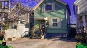 St. Catharines (Downtown) apartment for rent - A green house with a sign that says "REVEL Realty Inc., Brokerage".