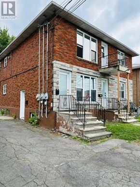Cornwall triplex for rent - A brick house with a white door and a black metal railing on the steps.
