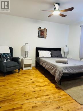 Cornwall triplex for rent - A bedroom with a bed, chair, and ceiling fan.