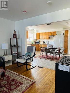 Cornwall triplex for rent - A living room with a chair and a table in front of a kitchen.