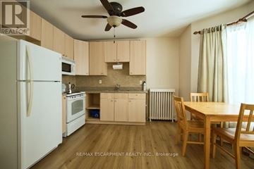 Hamilton (Blakeley) apartment for rent - A kitchen with a white refrigerator, wooden table and chairs, and a ceiling fan.