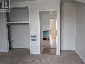 Oshawa (Central) multi-family for rent - A bedroom with a bed and a window is visible through an open door.