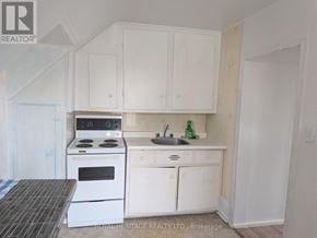 Oshawa (Central) multi-family for rent - A white kitchen with a stove, sink, and cabinets.