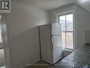 Oshawa (Central) multi-family for rent - A white refrigerator stands in a room with a tiled floor and a window.