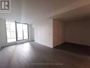 Toronto (Bay Street Corridor) condo for rent - A spacious room with wooden flooring and large windows.