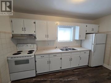 Welland (Welland Downtown) duplex for rent - A kitchen with white cabinets and appliances.