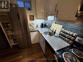 Toronto (Corso Italia-Davenport) fourplex for rent - A modern kitchen with a stainless steel refrigerator and a black stove top.