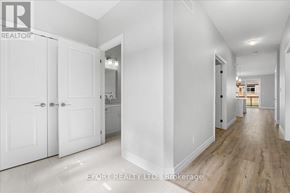 Quinte West (Murray Ward) townhouse for rent - A hallway with white walls and wooden floors leading to a kitchen area.