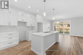 Quinte West (Murray Ward) townhouse for rent - A white kitchen with wooden floors and a large island in the middle.