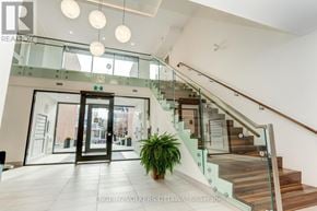 Ottawa multi-family for rent - A glass staircase with a wooden handrail and a potted plant on the landing.