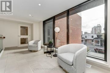 Ottawa multi-family for rent - A living room with a grey couch and a glass table with a lamp on it.