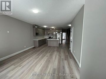 Welland (Lincoln/Crowland) townhouse for rent - A spacious room with wooden flooring and a kitchen area in the background.