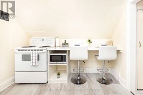 Ottawa apartment for rent - A kitchen with a white oven and microwave, a white table with two chairs, and a plant on the counter.