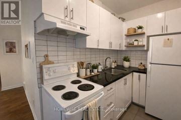 Toronto (South Parkdale) multi-family for rent - A kitchen with white cabinets and a black countertop.