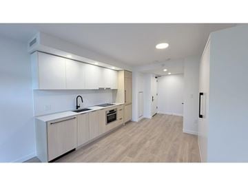 Surrey apartment for rent - A modern kitchen with white cabinets and a wooden floor.