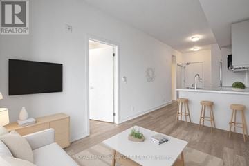 Clarington (Bowmanville) condo for rent - A living room with a white couch and a television mounted on the wall.