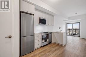 Clarington (Bowmanville) condo for rent - A modern kitchen with white cabinets and a wooden floor.