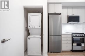 Clarington (Bowmanville) condo for rent - A white toilet is in a small room next to a stainless steel refrigerator.