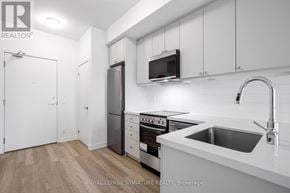 Clarington (Bowmanville) condo for rent - A kitchen with white cabinets and a stainless steel refrigerator.