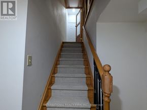 Vaughan (Crestwood-Springfarm-Yorkhill) apartment for rent - A staircase with a wooden handrail and grey carpeted steps.