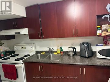 Markham (Cornell) townhouse for rent - A kitchen with a stove top oven, microwave, sink, and cabinets.