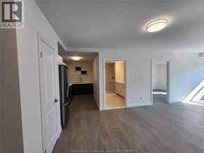 Windsor condo for rent - A spacious room with wooden flooring and white walls.