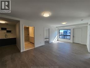 Windsor condo for rent - A spacious room with wooden flooring and a large window.