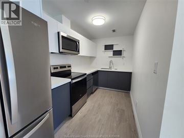 Windsor condo for rent - A kitchen with a stainless steel refrigerator and microwave.