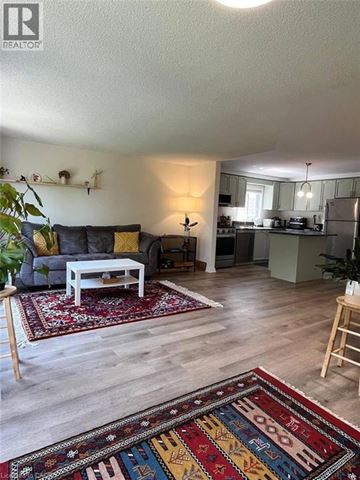 Waterloo townhouse for rent - A living room with a grey couch and a rug with a pattern of letters and numbers.