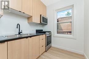 Hamilton (Stinson) multi-family for rent - A kitchen with wooden cabinets and a window showing a brick building outside.