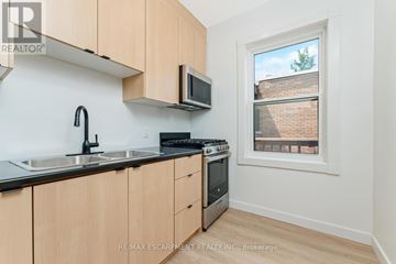Hamilton (Stinson) multi-family for rent - A kitchen with wooden cabinets and a window showing a brick building outside.