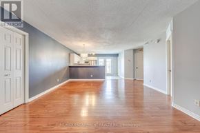 Burlington (Tansley) condo for rent - A spacious room with wooden floors and white walls.