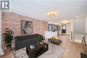 Hamilton apartment for rent - A living room with a grey couch and a coffee table in front of a brick wall.