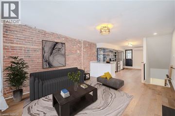 Hamilton apartment for rent - A living room with a grey couch and a coffee table in front of a brick wall.
