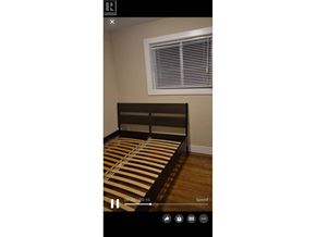 Burnaby apartment for rent - A bed with a striped bedspread is in the center of the image.