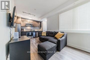 Toronto (Bayview Village) townhouse for rent - A living room with a black couch and a television on the wall.