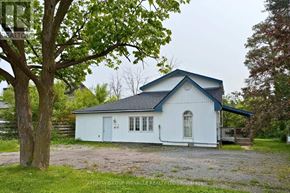 Kawartha Lakes (Lindsay) apartment for rent - A white house with a blue roof is surrounded by greenery.